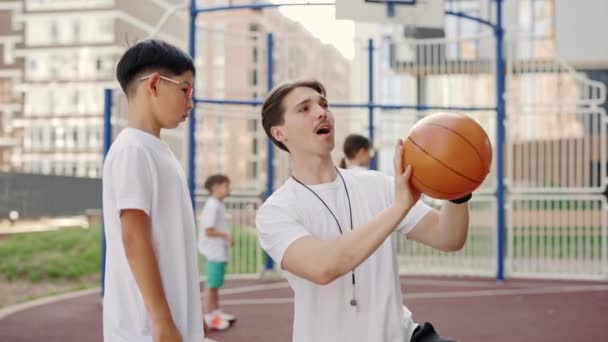 Handsome Male Coach Explaining Boy How Put Ball Basket Court — Αρχείο Βίντεο