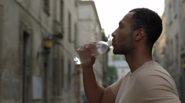 Kaçaktan sonra su içen koşucunun yan görüntüsü. İnsan susar ve koştuktan sonra su içer. Spor ve sağlıklı yaşam tarzı kavramı