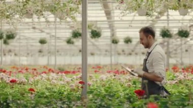 Serada elinde dijital tabletle dolaşan ve notlar alan bir erkek çalışanın yan görüntüsü. Halk ve meslek kavramı