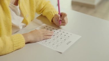 Close up of the girls pupil hands filling out answers . Hands of a female pupil doing test on the desk in the classroom. People and educational concept