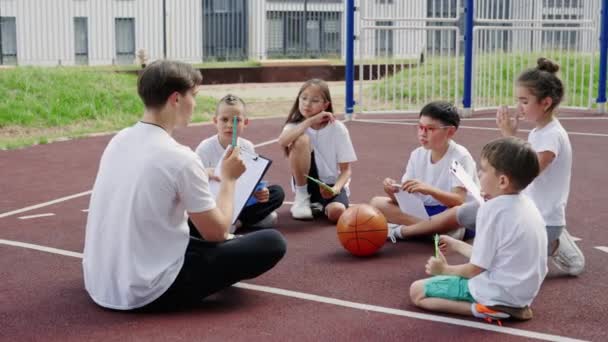 Male Trainer Explaining Game Strategy Kids Basketball Court Diverse Kids — ストック動画