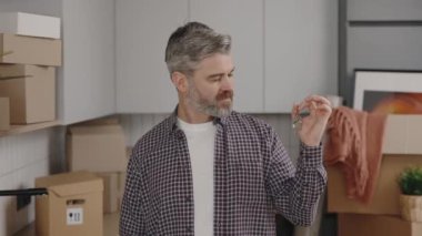 Portrait of happy man holding keys in hands, showing to camera. Smiling male renter tenant satisfied with moving into new apartment. New home and moving concept