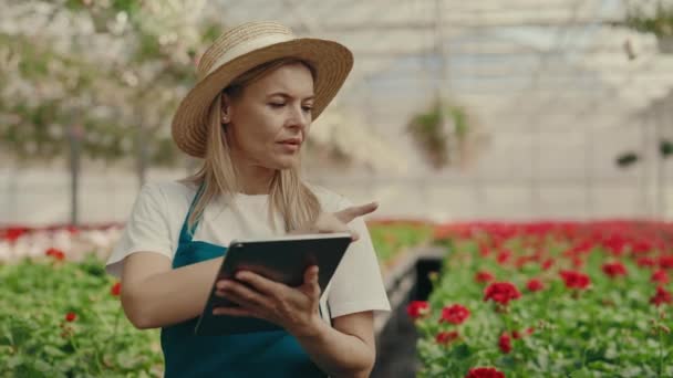 Female Gardener Holding Tablet Takes Inventory Flower Factory Standing Shelf — Stockvideo