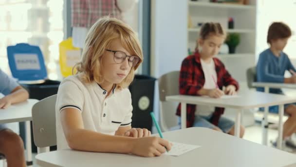 Red Head Pupil Wearing Glasses Sits Desk School Fills Out — Videoclip de stoc