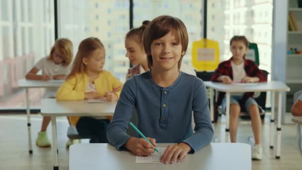 Portrait Male Smiled Pupil Looking Camera Sitting Desk Writing His — Vídeos de Stock