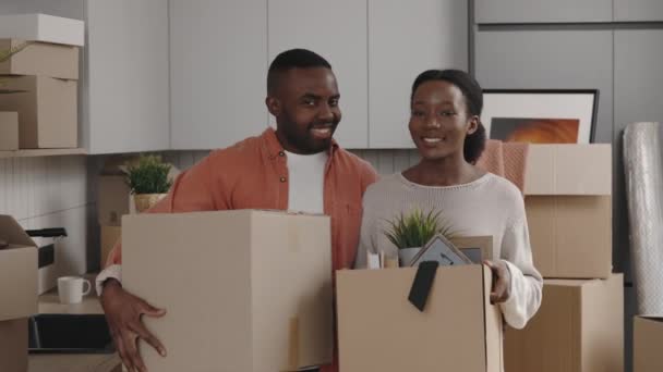 移転中の紙箱を持つカメラを見て笑顔幸せなカップルの肖像画 家族の暮らしと住宅のコンセプト — ストック動画