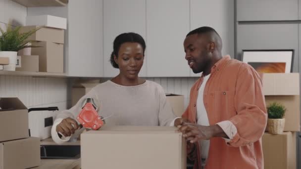 アフリカ系アメリカ人の夫婦は引越しのために荷物をまとめている 家族は彼らの項目を梱包し カートンボックスをタップ 準備だ 不動産コンセプト — ストック動画