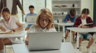 Okullu çocuk bilgisayar bilimleri dersi sırasında sınıfta oturup ödev yapıyor. İnsanlar ve teknoloji kavramı. İlköğretim sınıfı. Öğrenim ve eğitim kavramı