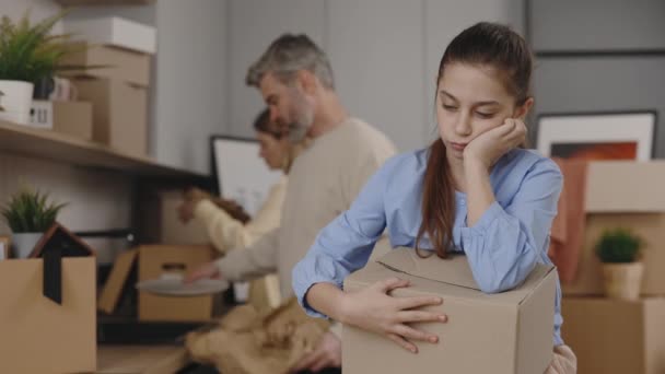 Filha Sentindo Entediada Apoiada Caixa Enquanto Seus Pais Desfazem Malas — Vídeo de Stock