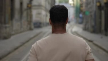 Kulaklıkla eski kasaba caddesinde koşan Afro-Amerikan adamın arka görüntüsü. Spor ve sağlıklı yaşam tarzı kavramı