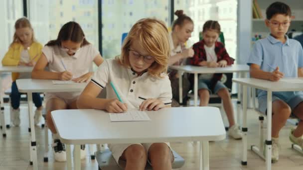 Examen Primaria Alumno Pelirrojo Con Gafas Sienta Primer Escritorio Aula — Vídeos de Stock