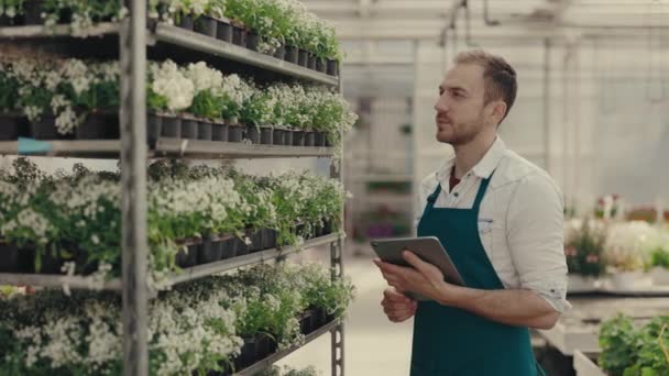 Κηπουρός Εξετάζει Λουλούδια Κρατώντας Την Ψηφιακή Ταμπλέτα Και Κοιτάζοντας Την — Αρχείο Βίντεο