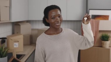 Afrika kökenli Amerikalı bir kadın elinde ev anahtarı ile kameraya bakıyor ve yeni evinde gülümsüyor. Kadın portre sahibi ayakta ve elinde anahtarlar var. Yeni ev ve taşınma konsepti