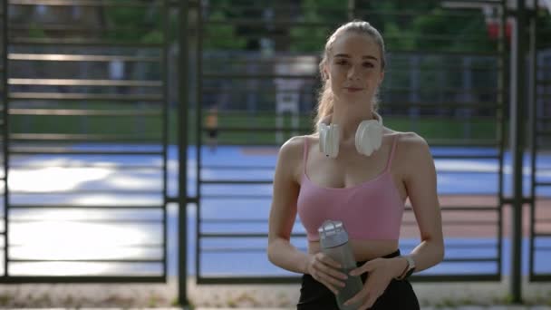 Retrato Joven Deportista Con Auriculares Cuello Sosteniendo Botella Deportiva Usando — Vídeos de Stock