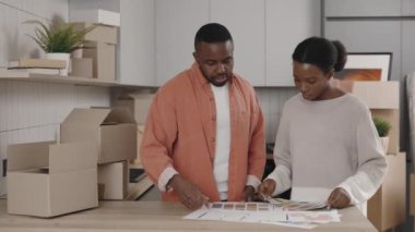 Afrikalı Amerikalı çift gelecekteki iç mekanlar için tasarım seçiyor. Mutlu çift ev tasarımından bahsediyor. Yeni ev ve taşınma konsepti