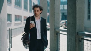 İş adamı iş merkezine gidiyor, sosyal medyadaki iş sohbetlerine cevap veriyor. Erkek patron iş yerinin yakınında akıllı telefon kullanıyor, müşterilerle mesajlaşıyor.
