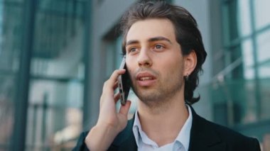 Beyaz iş adamı yürüyor, resmi takım elbise giyiyor ve müşterilerle telefonda konuşuyor. İş merkezinin yanındaki yakışıklı adam birini arıyor. Kapat.