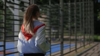 Spor sahasının yakınında koşan, özel spor giysiler giymiş bir kadının arka görüntüsü. Koşucu kadın dışarıda antrenman yapıyor. Spor ve sağlıklı yaşam tarzı kavramı