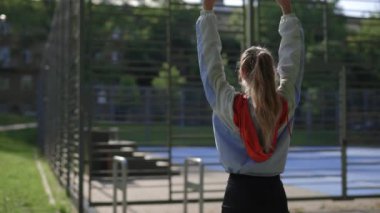 Koşmadan önce sırtını esneten beyaz bir genç kadın. Güzel, sportif sarışın antrenmandan önce ısınıyor. Spor ve sağlıklı yaşam tarzı kavramı