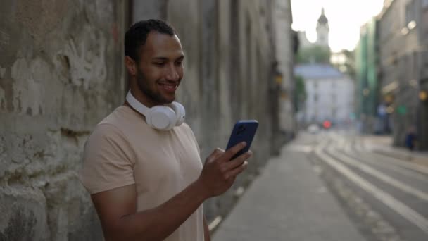 Portret Afroamerykanina Patrzącego Kamerę Trzymającego Telefon Komórkowy Hedfonach Stojących Centrum — Wideo stockowe