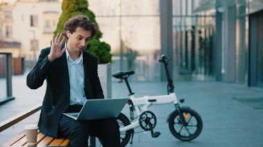 Laptop kullanan, uzaktan konferans veren, kameraya el sallayan, kulaklıklarını düzelten beyaz bir öğrenci. İnternette okuyan erkek öğrenci. İnsanlar ve teknoloji kavramı