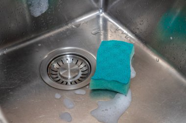 Mutfakta ıslak, paslanmaz lavabo, sünger ve köpük manzarası var. Ev ödevi ve temizlik tesisat konsepti