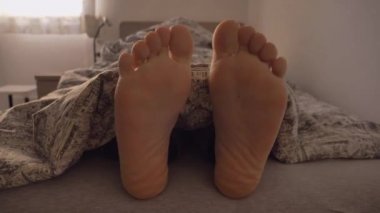 Close-up of happy feet dancing on the bed 