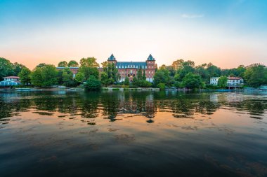 İtalya 'nın Torino kentindeki Valentino Kalesi' yle birlikte alacakaranlıkta Po nehrinin manzarası.