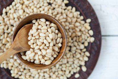 Çam fıstığı çekirdekleri kil tabakta, taze çam fıstıkları beyaz arka planda