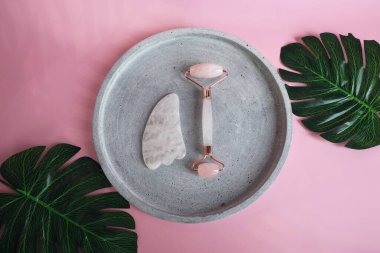 Yüz masajı seti. Yüz silindiri ve gua sha masaj aleti, doğal pembe taşlardan yapılmış, refah, yüz fitness konsepti, şık tek renkli kart, lüks afiş.