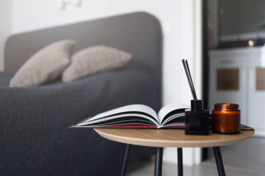 An open magazine on the coffee table with a candle and an aroma diffuser in the bedroom. Home cozy photography.