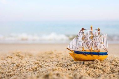 Toy ship on the sand by the sea. Summer vacation concept
