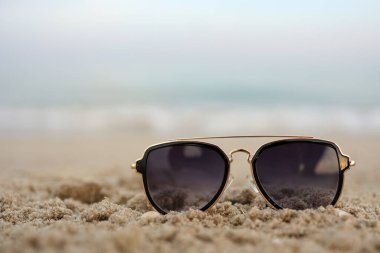 Beautiful background of Turquoise Sea with sunglasses lying on the sand beach. The concept of Rest Vacation. Wide Horizontal Colorful Wallpaper with selective focus and copy space.