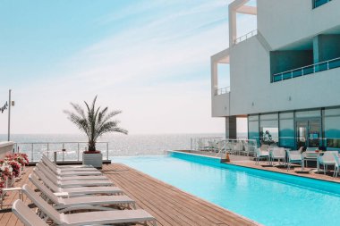 Summer outdoor swimming pool and sun loungers. In the hotel to rest. Seaview landscape.
