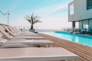 Summer outdoor swimming pool and sun loungers. In the hotel to rest. Seaview landscape.