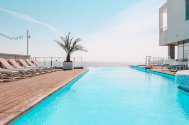 Summer outdoor swimming pool and sun loungers. In the hotel to rest. Seaview landscape.