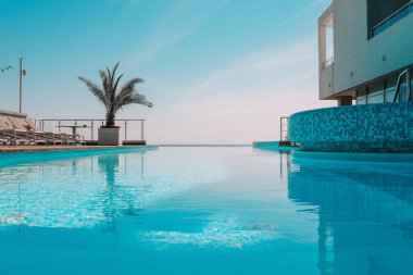 Summer outdoor swimming pool and sun loungers. In the hotel to rest. Seaview landscape.