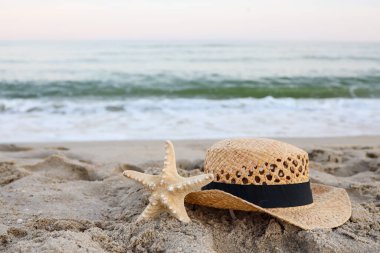 Straw hat and starfish on beautiful sand by the sea