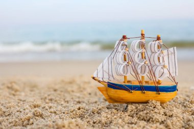 Toy ship on the sand by the sea. Summer vacation concept