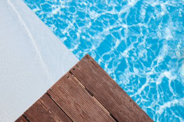 Wooden platform on swimming pool background. Pool background wallpaper. Space for text.
