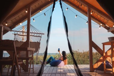 The girl takes pictures of a beautiful view on vacation in the glamping.