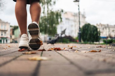 Close up of feet of a runner running in autumn leaves training for marathon and fitness healthty lifestyle. City run marathon.