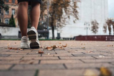 Close up of feet of a runner running in autumn leaves training for marathon and fitness healthty lifestyle. City run marathon.