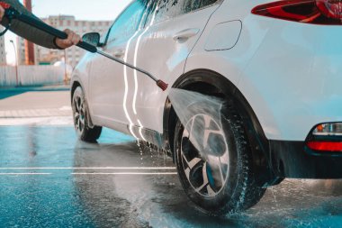 Manual car wash with pressurized water in car wash outside. Summer Car Washing. Cleaning Car Using High Pressure Water. Washing with soap. Close up concept.