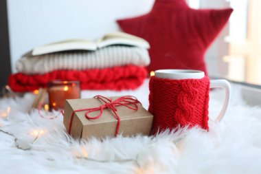 Red knitted cup with a drink on a Christmas background. New Year's home comfort.
