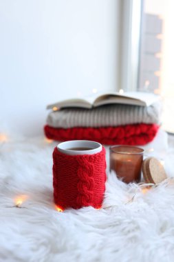 Red knitted cup with a drink on a Christmas background. New Year's home comfort.