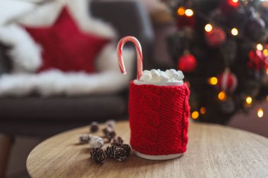 Christmas cup of cocoa with marshmallows, on a wooden table against the background of a Christmas tree. New Year's mood.