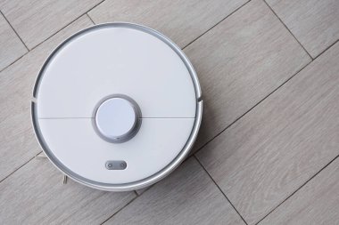 Robot vacuum cleaner removes dust in room on floor. Vacuum cleaner in ordinary apartment. modern household wireless device for cleaning house. smart home concept.