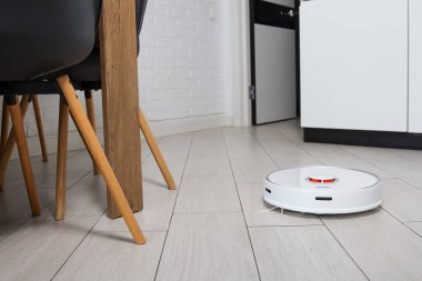 Robot vacuum cleaner removes dust in room on floor. Vacuum cleaner in ordinary apartment. modern household wireless device for cleaning house. smart home concept.
