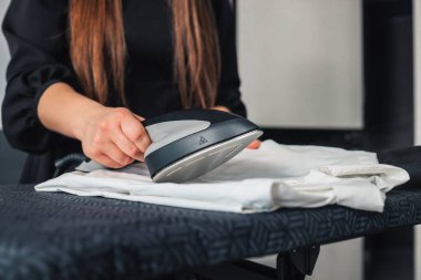 Steam iron in the hands of a girl who irons clothes.